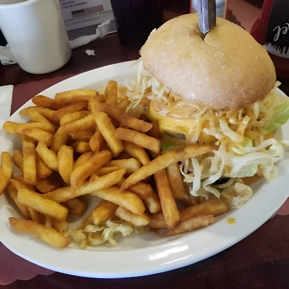A Polish Villa burger with cheese, shredded lettuce, and a side of golden french fries.